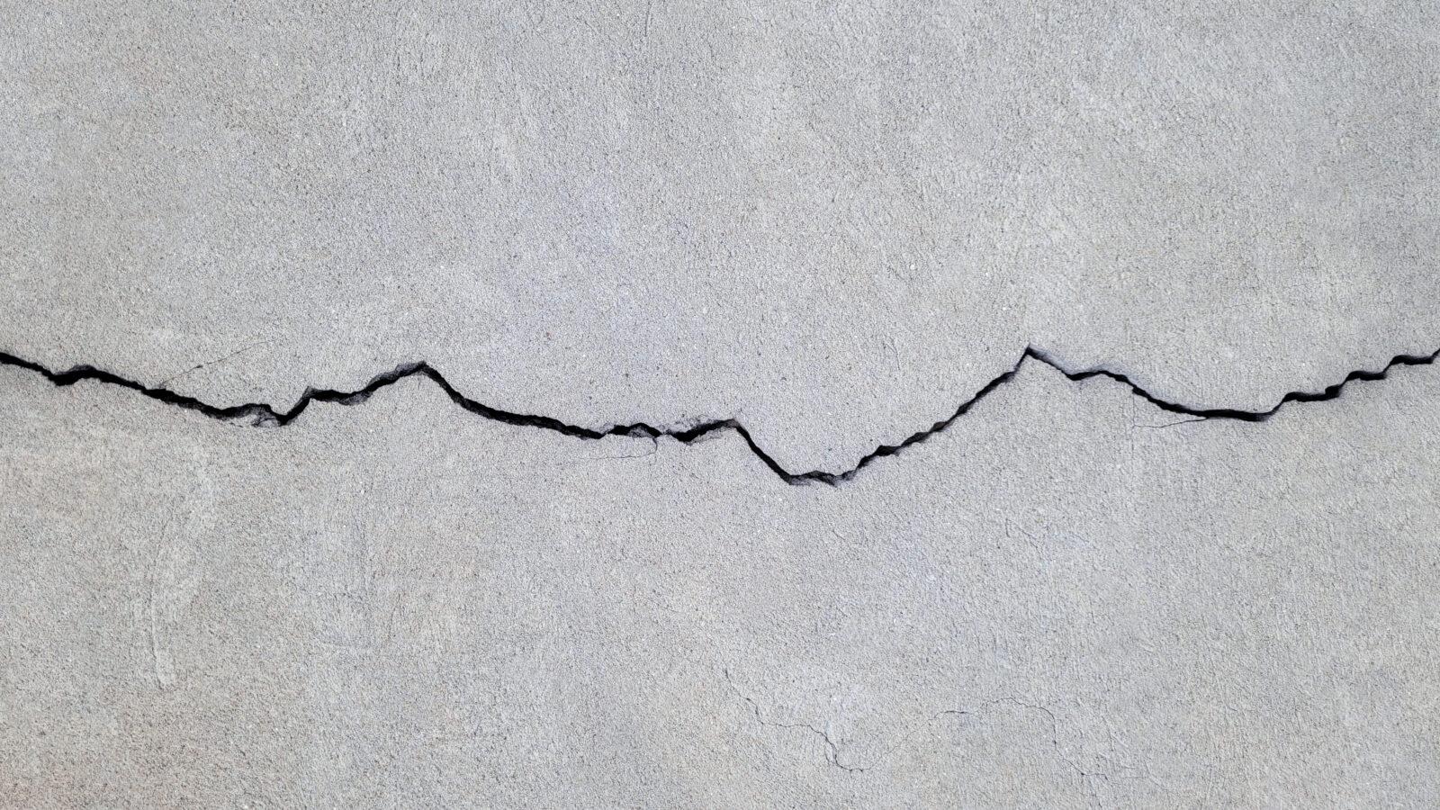 A long horizontal crack running across a concrete wall surface